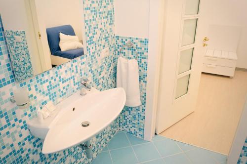 a blue tiled bathroom with a sink and a mirror at B & B Sotto la Volta in Massafra