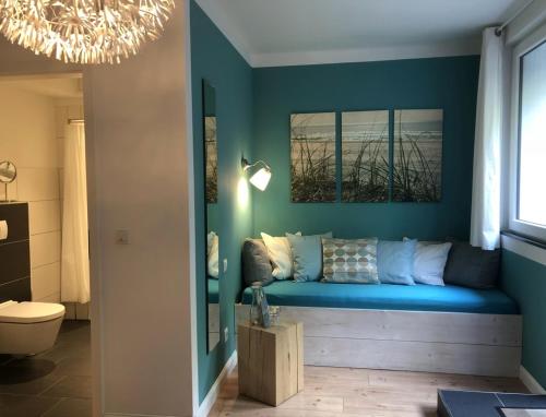 sala de estar con sofá azul y ventana en Haus am See B&B en Bornheim