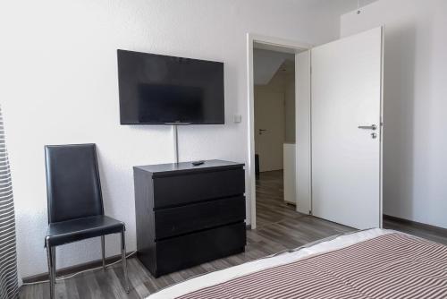 a bedroom with a dresser with a television and a chair at Business Wohnung ++ hochwertige Ausstattung in Paderborn
