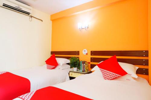 two beds in a room with red and white pillows at Shenzhen Xin Xiang Yue Inn in Shenzhen