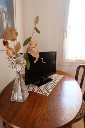 サン・ドナ・ディ・ピアーヴェにあるRed Feniceの花瓶とテレビが置かれた木製のテーブル