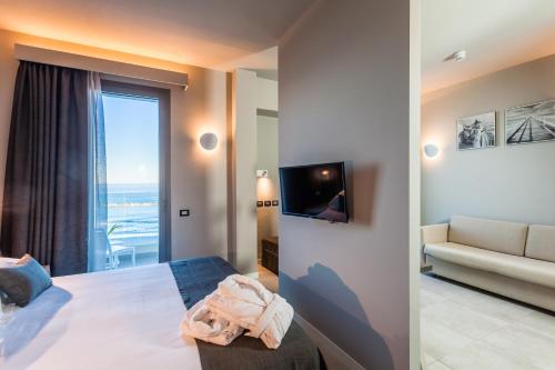a bedroom with a bed and a couch and a television at Nautilus Family Hotel in Pesaro