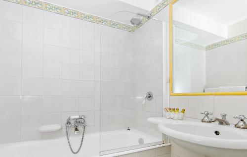 a white bathroom with a shower and a sink at Hotel Minerva in Sorrento