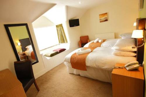 a hotel room with a large bed and a mirror at Rose And Crown in Porthcawl