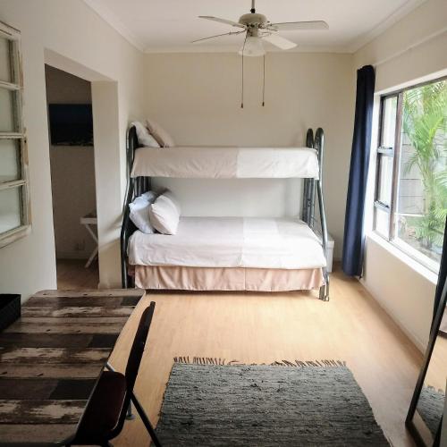two bunk beds in a room with a ceiling fan at Vincentia Odd Cottage ( self catering) in East London