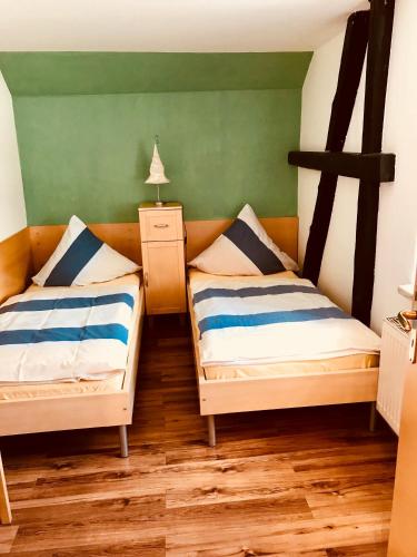 two beds in a room with green walls and wooden floors at Ferienwohnungen "Am Mühlteich" in Radeburg