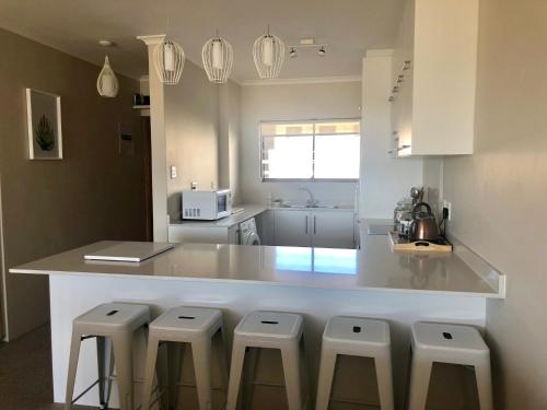 a kitchen with a counter with stools around it at Beachfront Apartment at Malata Beach in Blouberg in Bloubergstrand