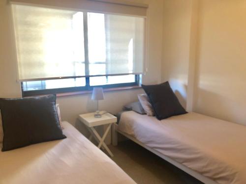two beds in a small room with a window at Beachfront Apartment at Malata Beach in Blouberg in Bloubergstrand