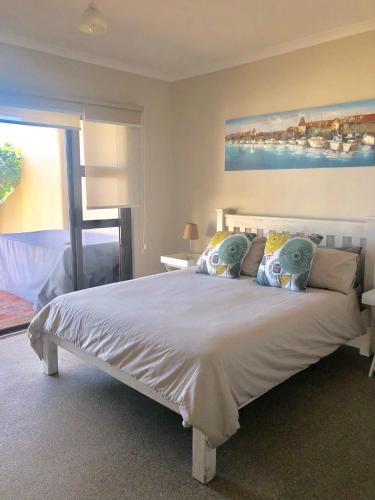 a bedroom with a large white bed with pillows at Beachfront Apartment at Malata Beach in Blouberg in Bloubergstrand