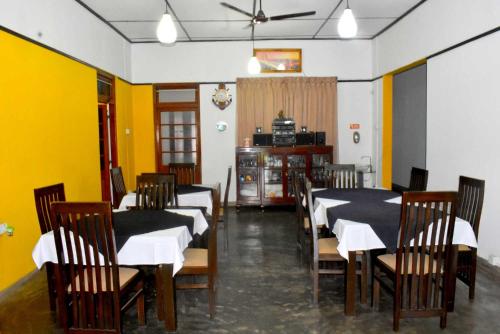 uma sala de jantar com mesas e cadeiras e paredes amarelas em Old Park Villa em Jaffna
