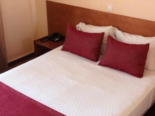 a bedroom with a bed with red pillows at Imperio Hotel in Peso da Régua