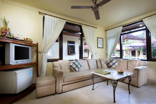 a living room with a couch and a tv at Bali Seascape Beach Club in Candidasa