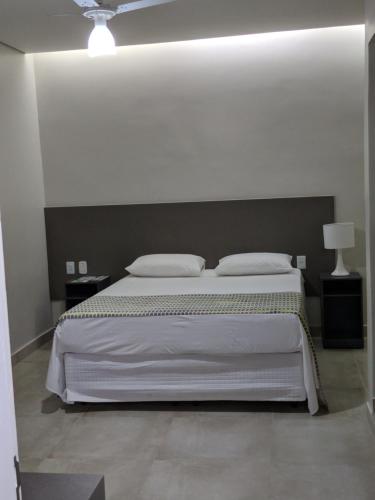 a bedroom with a large white bed with two pillows at Hotel Ouro Verde in Três Pontas