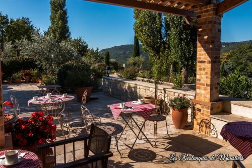 a patio with tables and chairs and a stone wall at Hotel Les Restanques De Moustiers in Moustiers-Sainte-Marie
