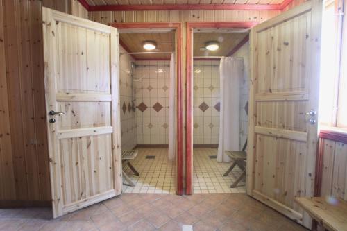 a bathroom with two showers with wooden doors at Saiva Camping & Stugby in Vilhelmina