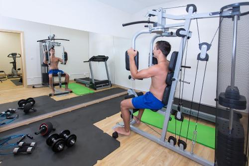 a man in a gym doing squats on a reformer at Apartments Villa Loznica in Brela