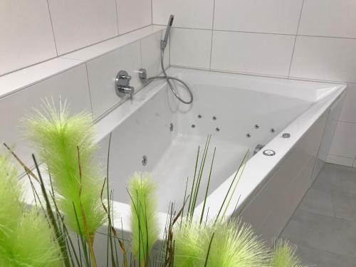 La salle de bains est pourvue d'une baignoire blanche et de plantes vertes. dans l'établissement Komfort-Ferienwohnung Wellenbrecher by Meer-Ferienwohnungen, à Olpenitz