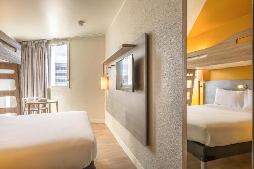 ジュヌヴィリエにあるibis budget Paris Gennevilliersのベッド2台とテーブルが備わるホテルルームです。