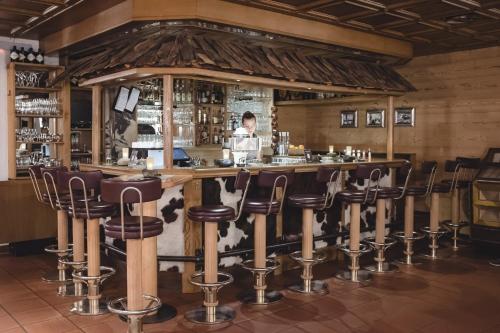 a bar with leather stools in a restaurant at Aktiv & Spa Hotel Alpenrose in Schruns-Tschagguns