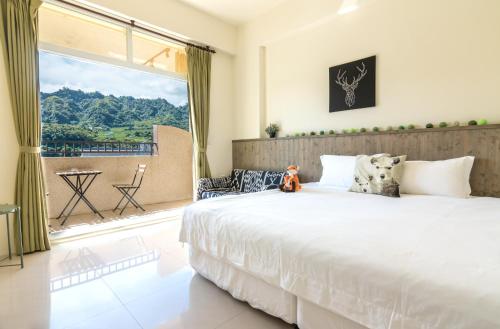 a bedroom with a large bed and a large window at Cozy Green Guesthouse in Taitung City