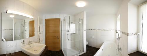 a bathroom with a shower and a sink and a bath tub at Haus Schmetterling in Alpbach