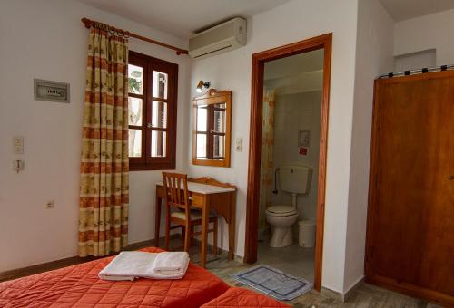 a bedroom with a bed and a table and a toilet at Hotel Lofos - The Hill in Ios Chora