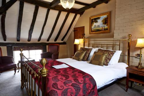 a bedroom with a large bed with a red blanket at The Coleshill by Greene King Inns in Coleshill