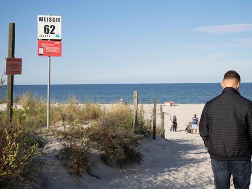 a man standing on the beach looking at the ocean at Dariusz Apartament PREMIUM Jurata z garażem in Jurata