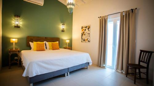 sypialnia z łóżkiem z żółtymi poduszkami i oknem w obiekcie Herdade dos Alfanges "THE FARMHOUSE" w mieście Vila Nova da Baronia