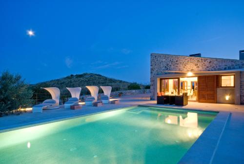 a swimming pool with chairs and a house at Cases de Son Barbassa Hotel & Restaurant in Capdepera