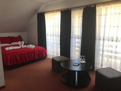 a bedroom with a bed and a table and curtains at Pensiunea Domnika in Dej