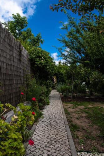 un camino de piedra junto a una valla y flores en Casa da Anita, en Aldeia do Meco