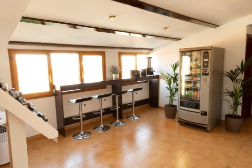 a room with a bar with stools and a refrigerator at Hostal Legaz in Funes