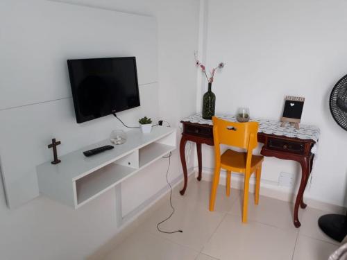 Habitación blanca con escritorio, TV y silla. en Kitnet Arraial do Cabo Praia Grande, en Arraial do Cabo