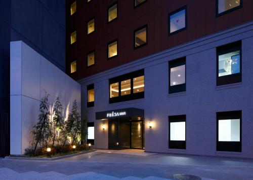 un edificio con entrada a un hotel por la noche en Sotetsu Fresa Inn Yokohama Sakuragi-cho en Yokohama