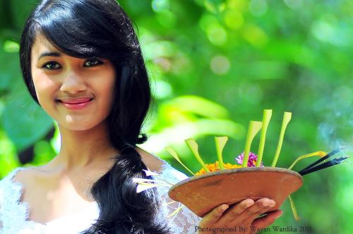 a woman is holding a bowl with flowers in it at Tegal Dukuh Camp in Tegalalang