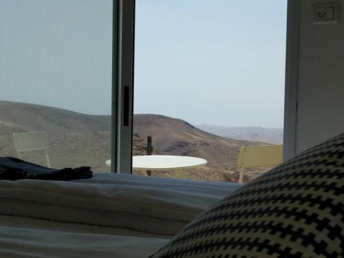 a bedroom with a bed and a view of the desert at Dead Sea Desert's Edge in Arad