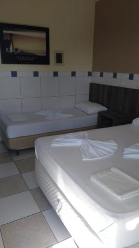 a room with three beds and a tv on the wall at Ville House Hotel Canoas in Canoas