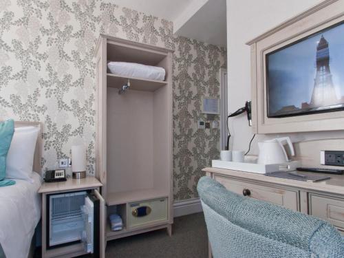 a bedroom with a tv and a bed and a chair at W12 Rooms in London