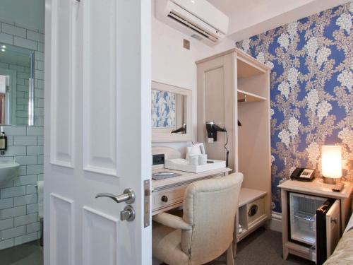 uma casa de banho com um lavatório e uma secretária com uma cadeira. em W12 Rooms em Londres