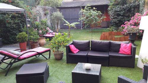 Un patio con un sofá negro y algunas plantas. en Les Lamartine-chambres d'hôtes, en Le Mans