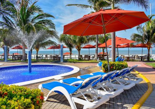 een groep stoelen en een parasol naast een zwembad bij Mar & Sol, Hotel y resturante in La Unión