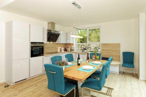 a kitchen and dining room with a wooden table and blue chairs at Kapitaensweg 32 in Ostseebad Karlshagen