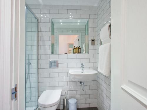 a white bathroom with a sink and a mirror at W12 Rooms in London