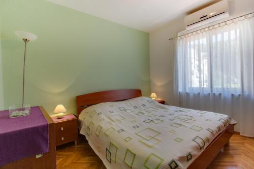 a bedroom with a bed and a table and a window at Andrino in Mali Lošinj