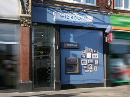 a store front with a blue door with signs on it at W12 Rooms in London