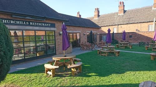 un grupo de mesas de picnic y sombrillas púrpuras en un patio en Blue Boar Inn en Atherstone