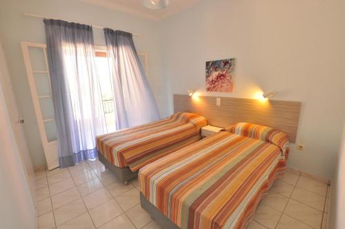 a hotel room with two beds and a window at Elena Apartments Corfu in Acharavi