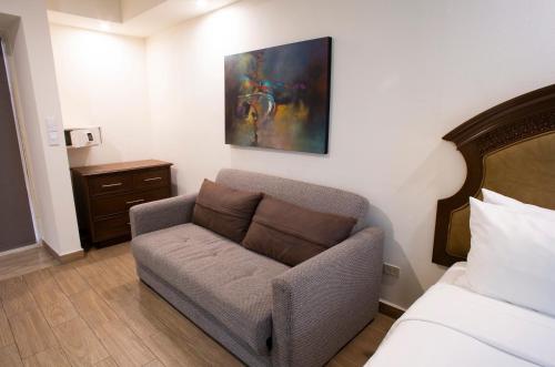 a living room with a couch and a painting on the wall at Best Western PLUS Monterrey Colón in Monterrey