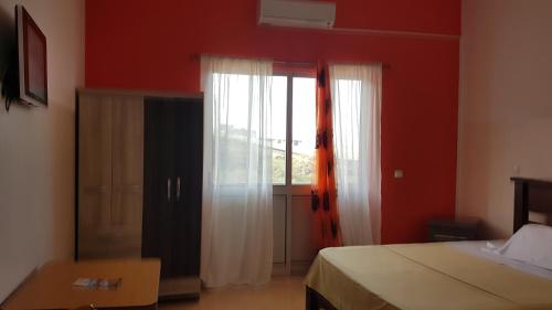 a bedroom with a bed and a window with white curtains at Hotel Ocean View & Restaurante Seafood in São Filipe